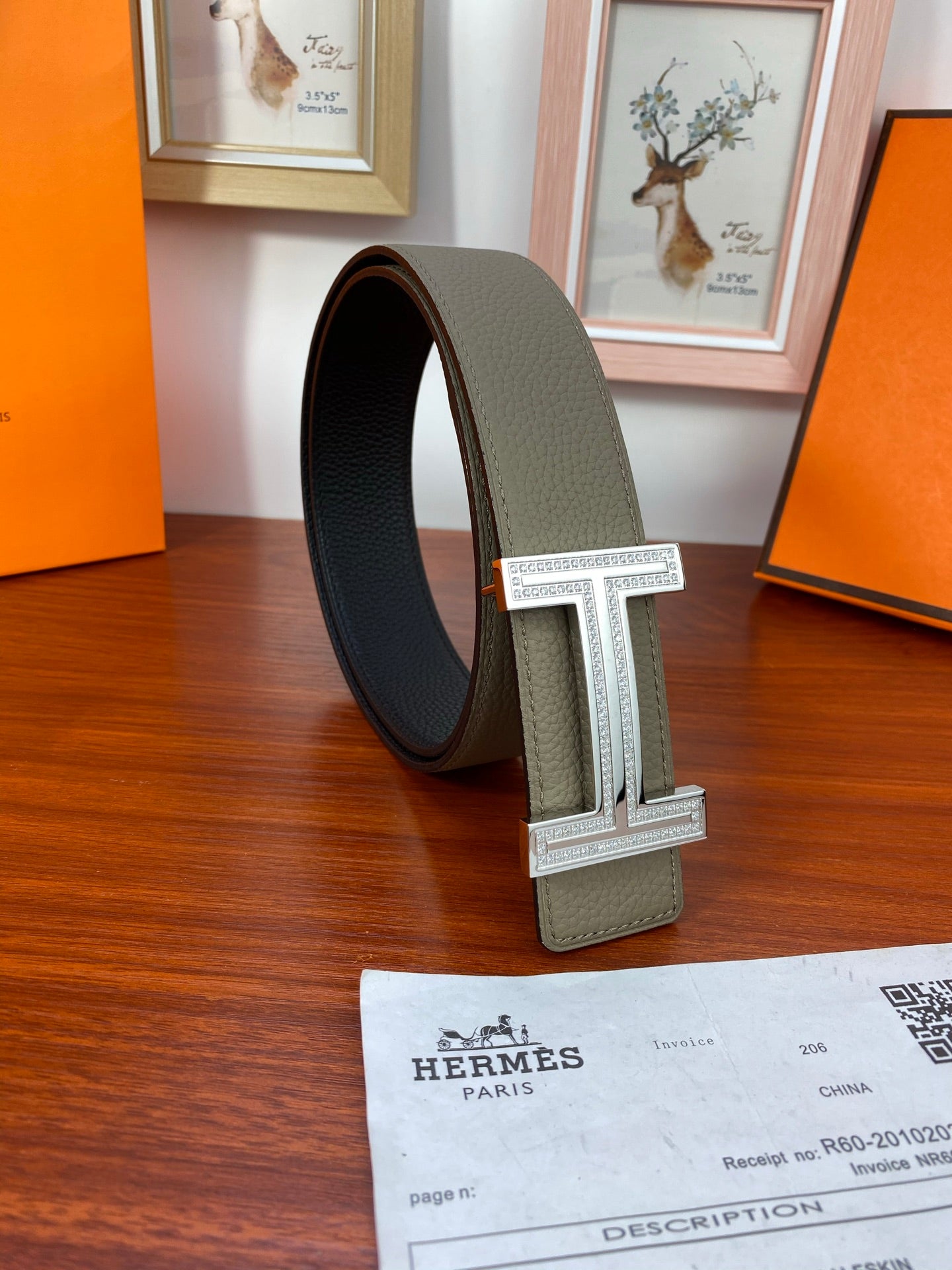 Leather belt looped around, light gray strap with dark reverse and silver H buckle