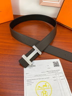 Dark leather belt with silver H buckle and keeper, laid flat