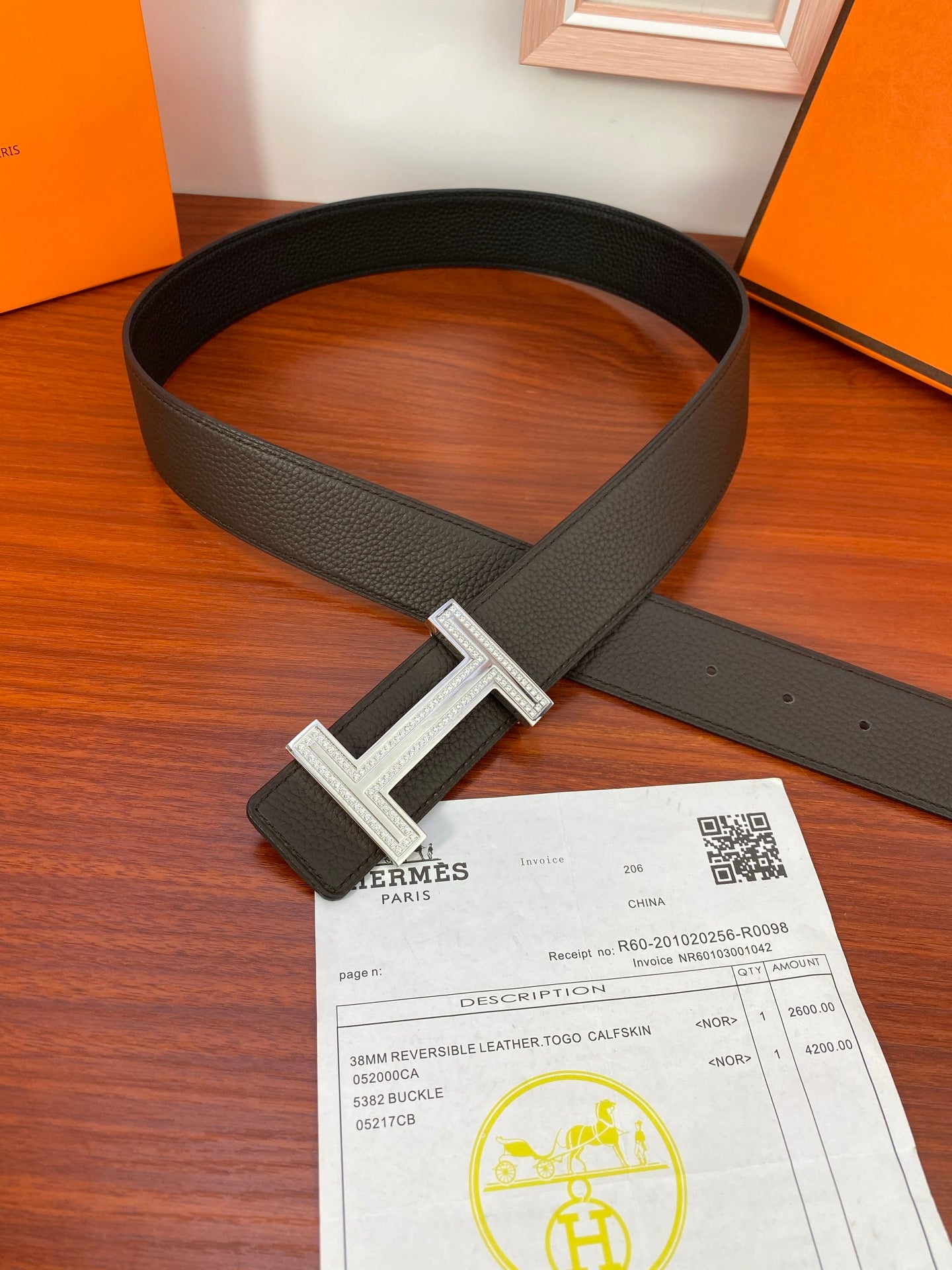 Dark leather belt with silver H buckle and keeper, laid flat