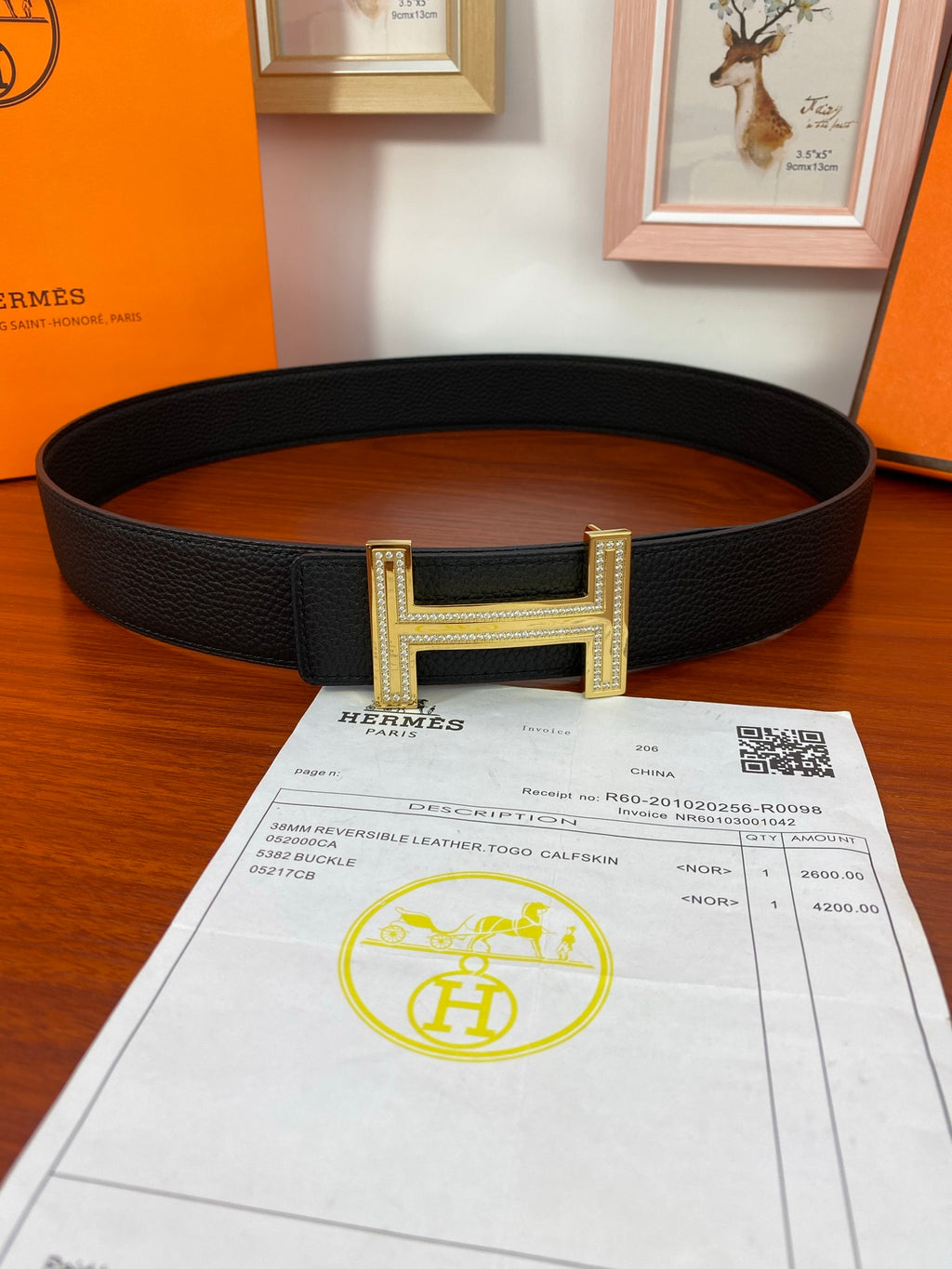 Black leather belt with gold-tone H buckle, flat lay view
