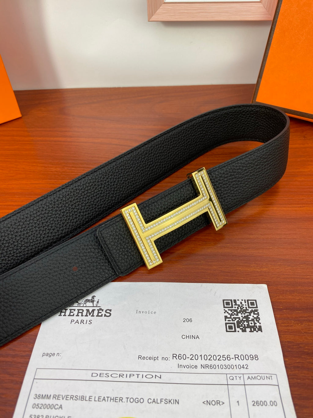 Black leather belt with gold-tone H buckle, close-up on buckle frame