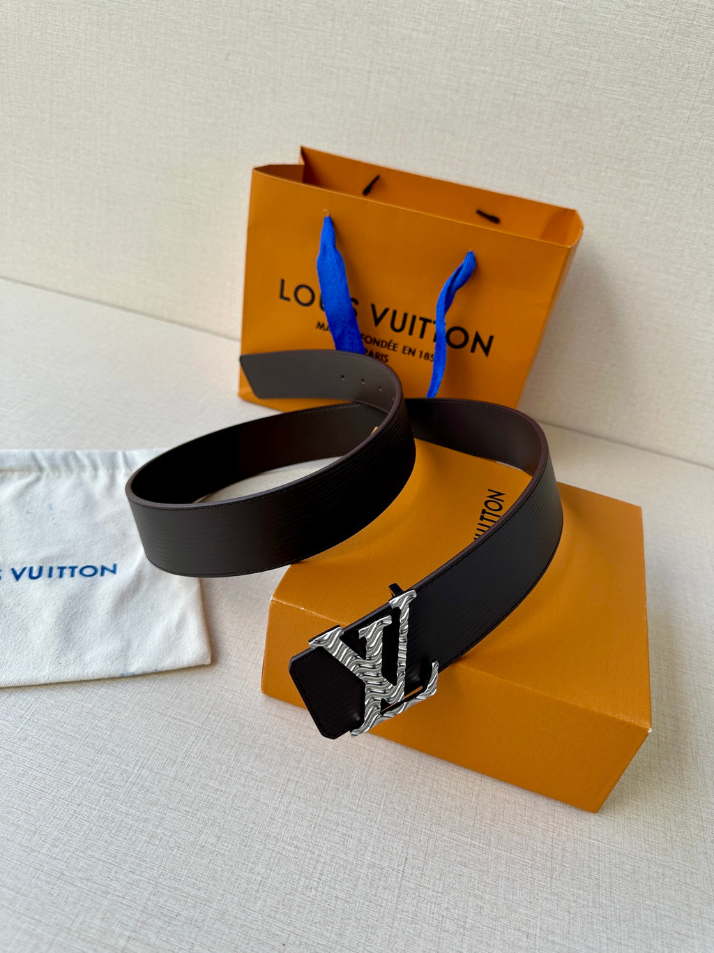 Louis Vuitton belt coiled with dark strap and silver-tone LV buckle detail
