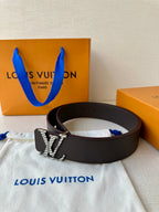 Louis Vuitton belt with dark strap and gold-tone LV buckle, laid on fabric