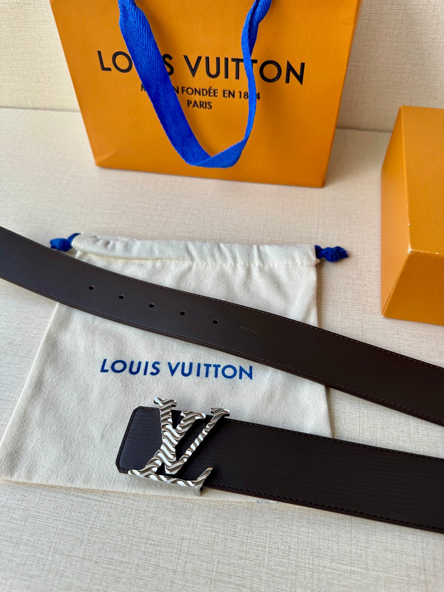 Louis Vuitton belt flat on cloth: dark strap with zebra-style LV buckle