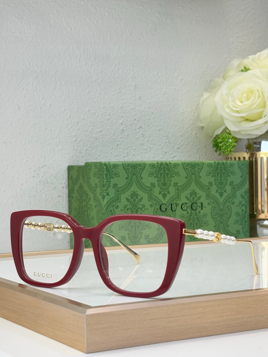 Gucci glasses with green-tinted lenses, maroon square frames, and pearl-bead detail