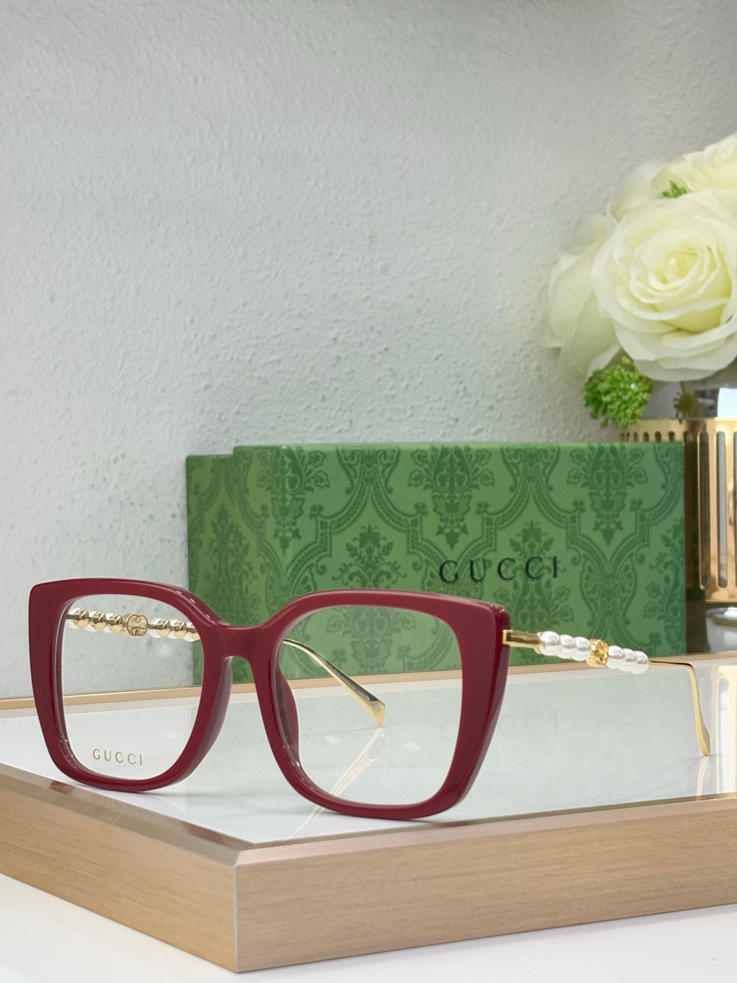 Gucci glasses with green-tinted lenses, maroon square frames, and pearl-bead detail