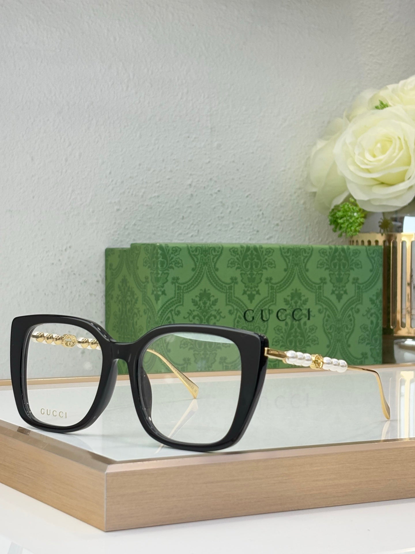 Gucci glasses with clear lenses, black square frames, and gold-tone temple accents
