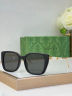 Gucci glasses with dark lenses, black square frames, and gold-tone temple accents