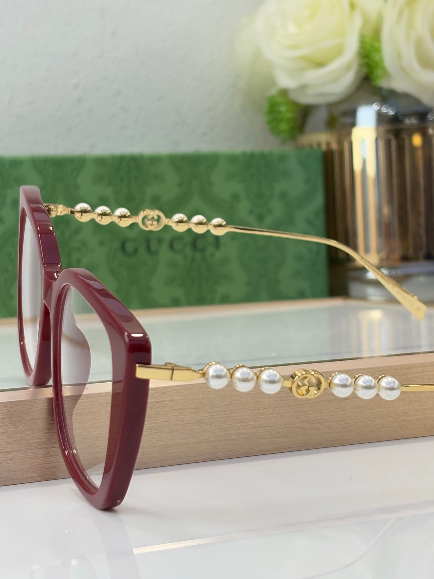 Gucci glasses in maroon with pearl-and-gold bead chain on the temple arm