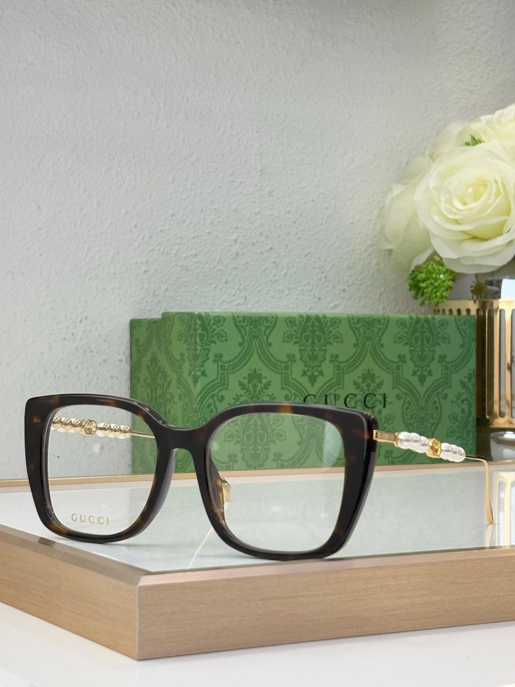 Gucci glasses with dark lenses, black square frames, and pearl-bead temple detail