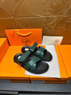 Hermes green slide sandals with double wide straps over black rubber soles