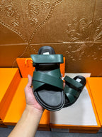 Hermes teal green sandals held up, showing wide strap and black footbed