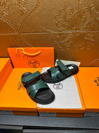 Hermes teal green sandals with wide straps and black sole, shown on packaging