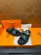 Hermes slide sandals featuring teal green straps over black cushioned footbeds