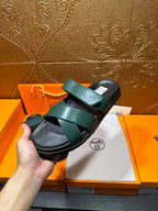 Hermes teal green sandals in hand, wide strap across top with black sole