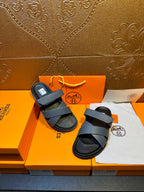 Hermes slide sandals with navy crossover straps and black footbeds, laid out