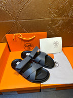 Hermes slide sandals with wide navy strap over black sole, paired