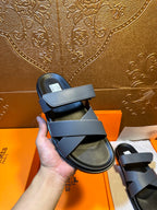 Hermes slide sandal held up, navy strap and black footbed