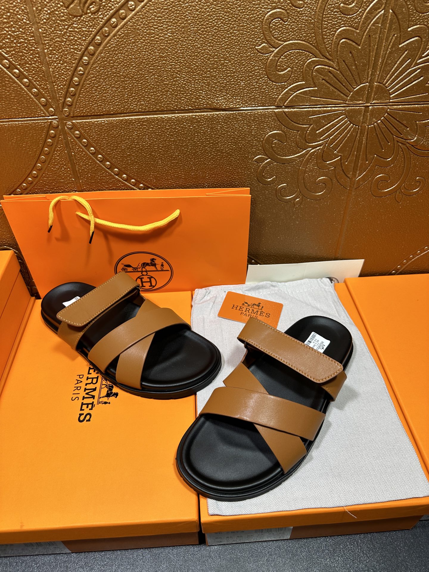 Hermes sandals pair with tan wide straps and black footbeds on box