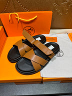 Hermes slide sandals with tan wide straps and black footbeds, side view