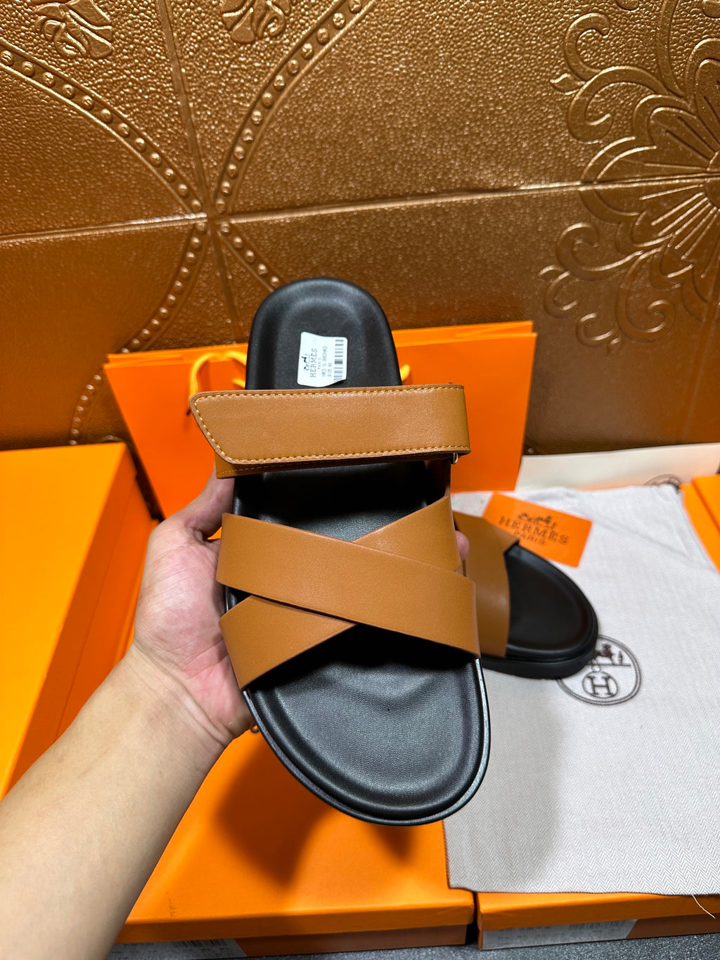 Hermes slide sandals pair with tan straps over black footbeds, front view