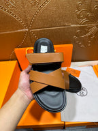 Hermes slide sandals pair with tan straps over black footbeds, front view