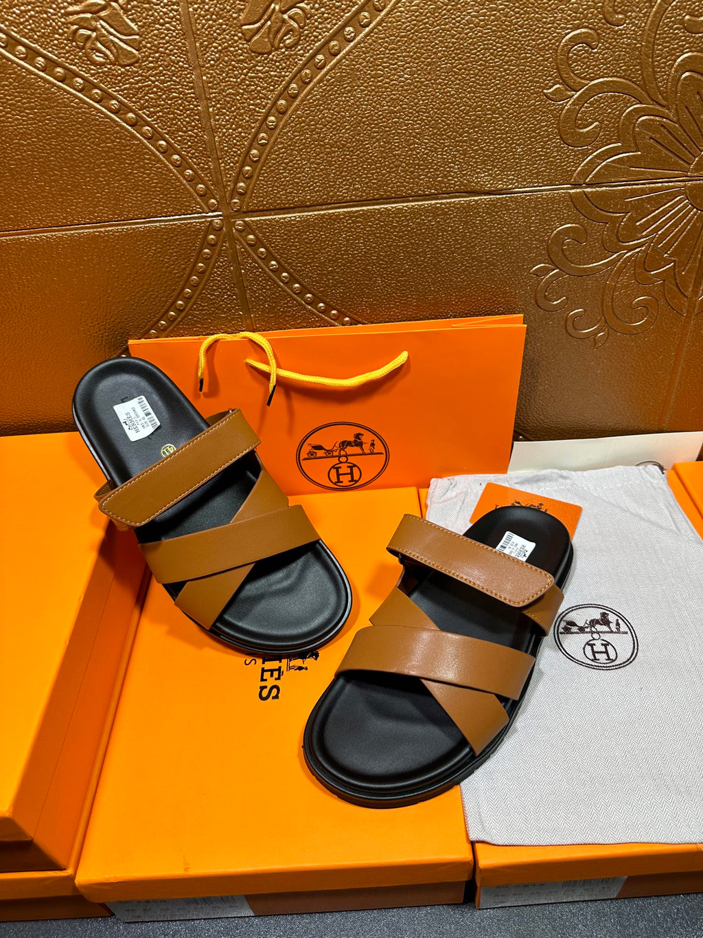 Hermes sandals pair with tan straps and black footbeds, both laid out