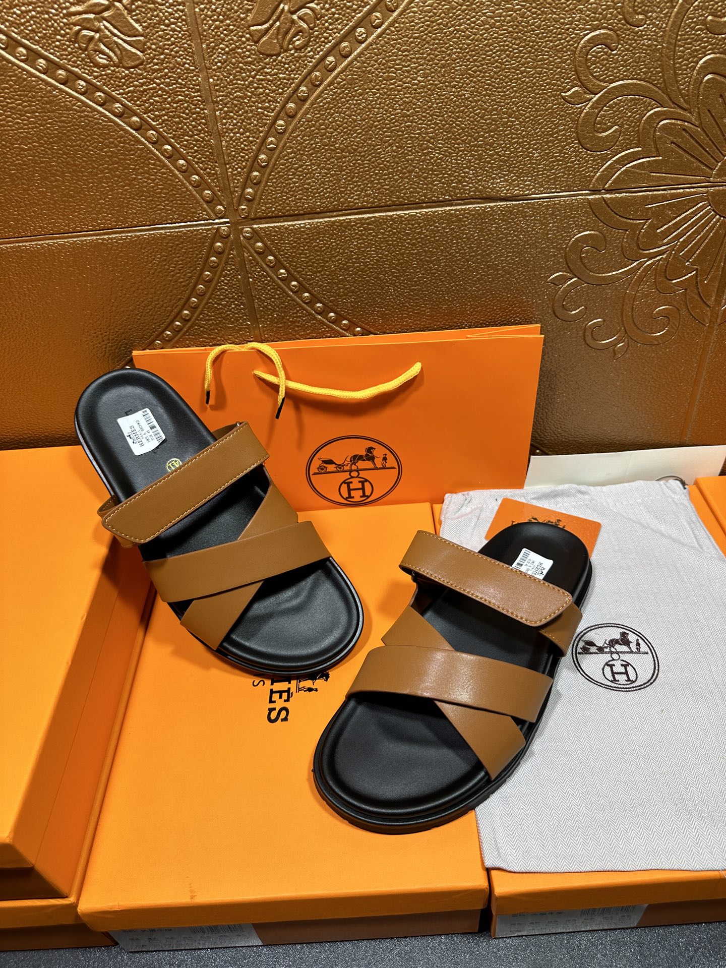 Hermes sandals pair with tan straps and black footbeds, both laid out