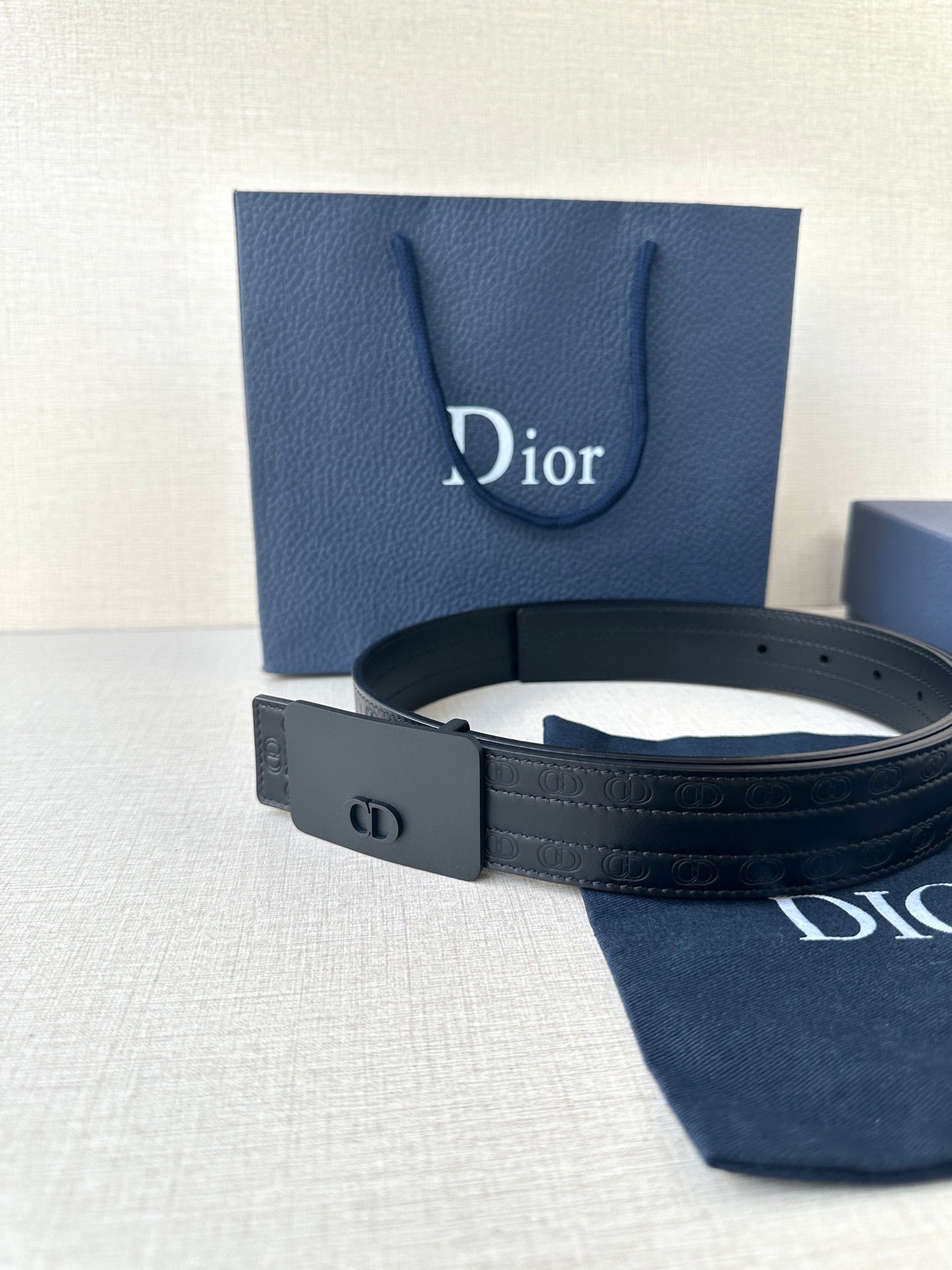 Leather belt with navy strap and matte dark buckle; includes belt keeper loop