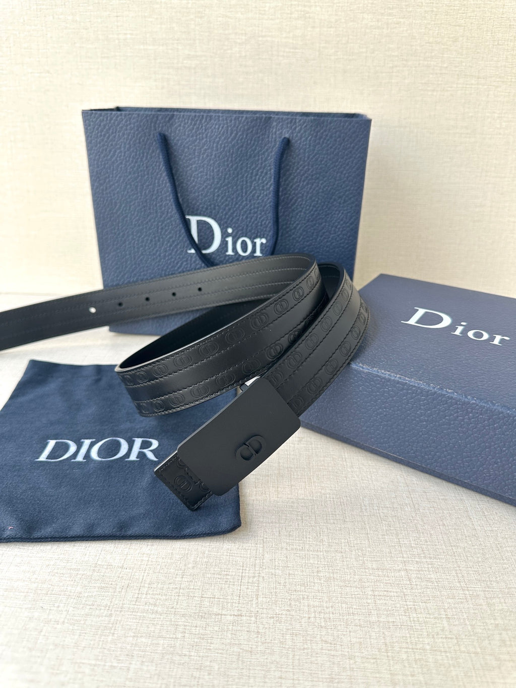 Leather belt with navy strap, dark rectangular buckle, and punched adjustment holes