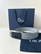 White leather belt with dark buckle and embossed strap pattern, angled close view
