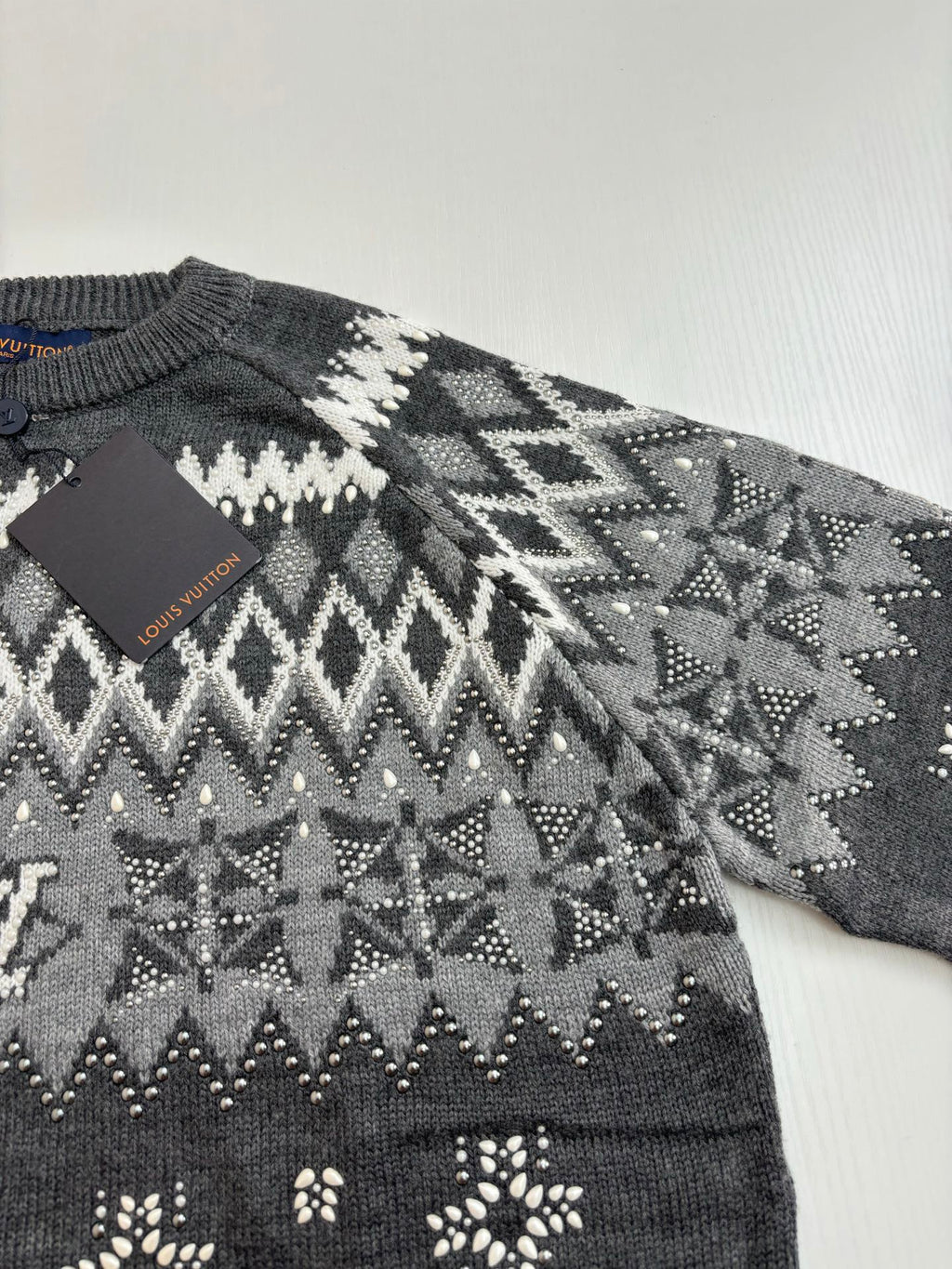 Dark gray knit sweater with white fair isle pattern and small decorative motifs