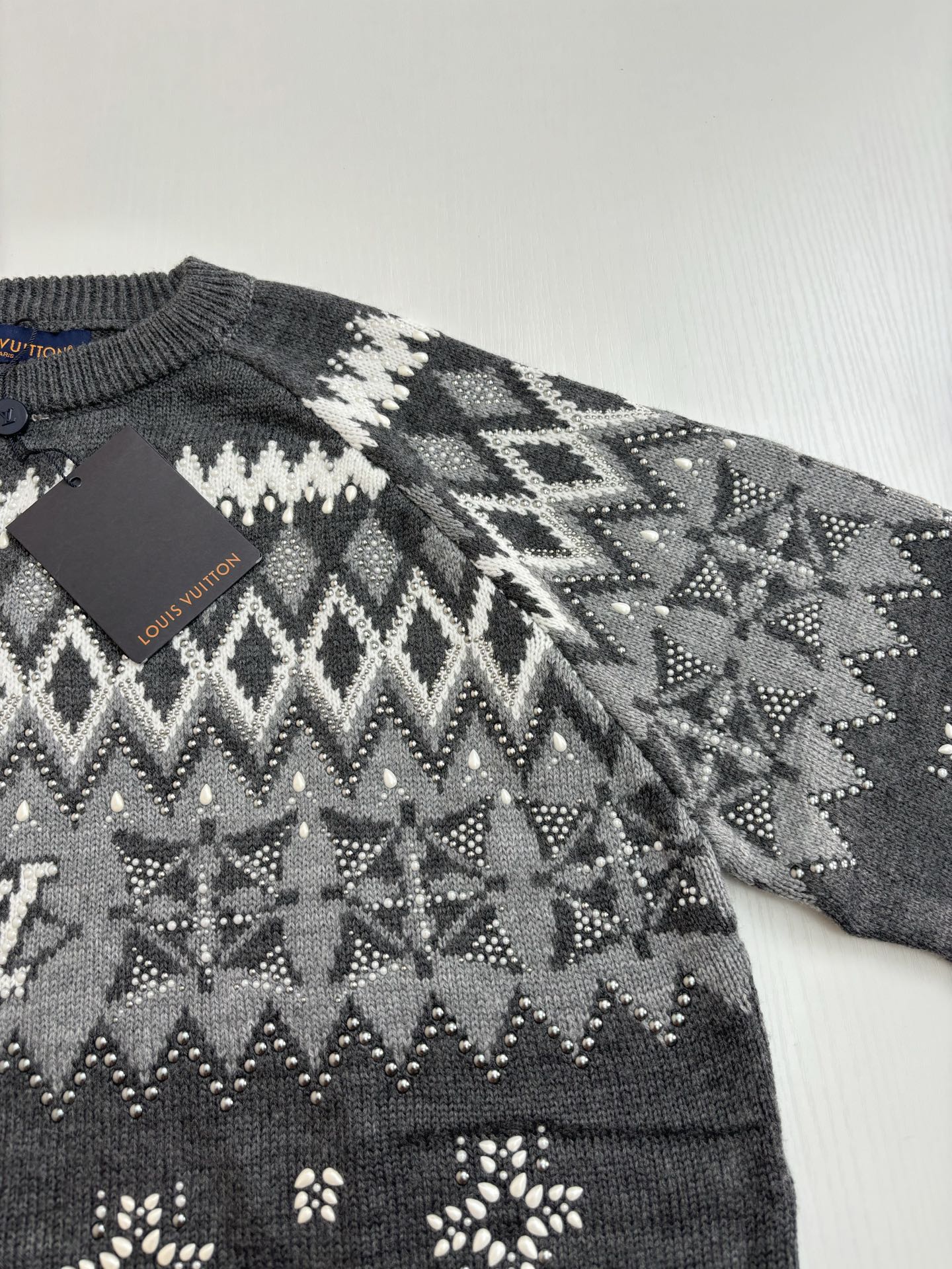 Dark gray knit sweater with white fair isle pattern and small decorative motifs