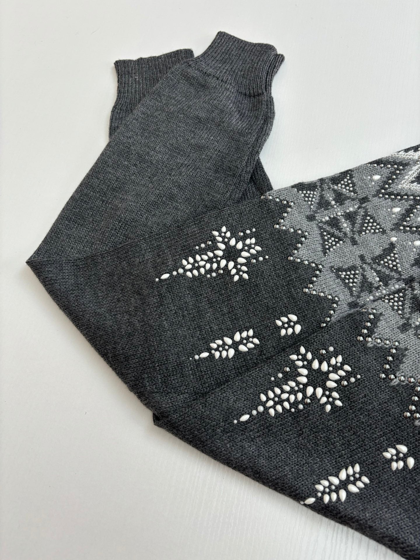 Folded dark gray knit sweater with white fair isle pattern and decorative motifs