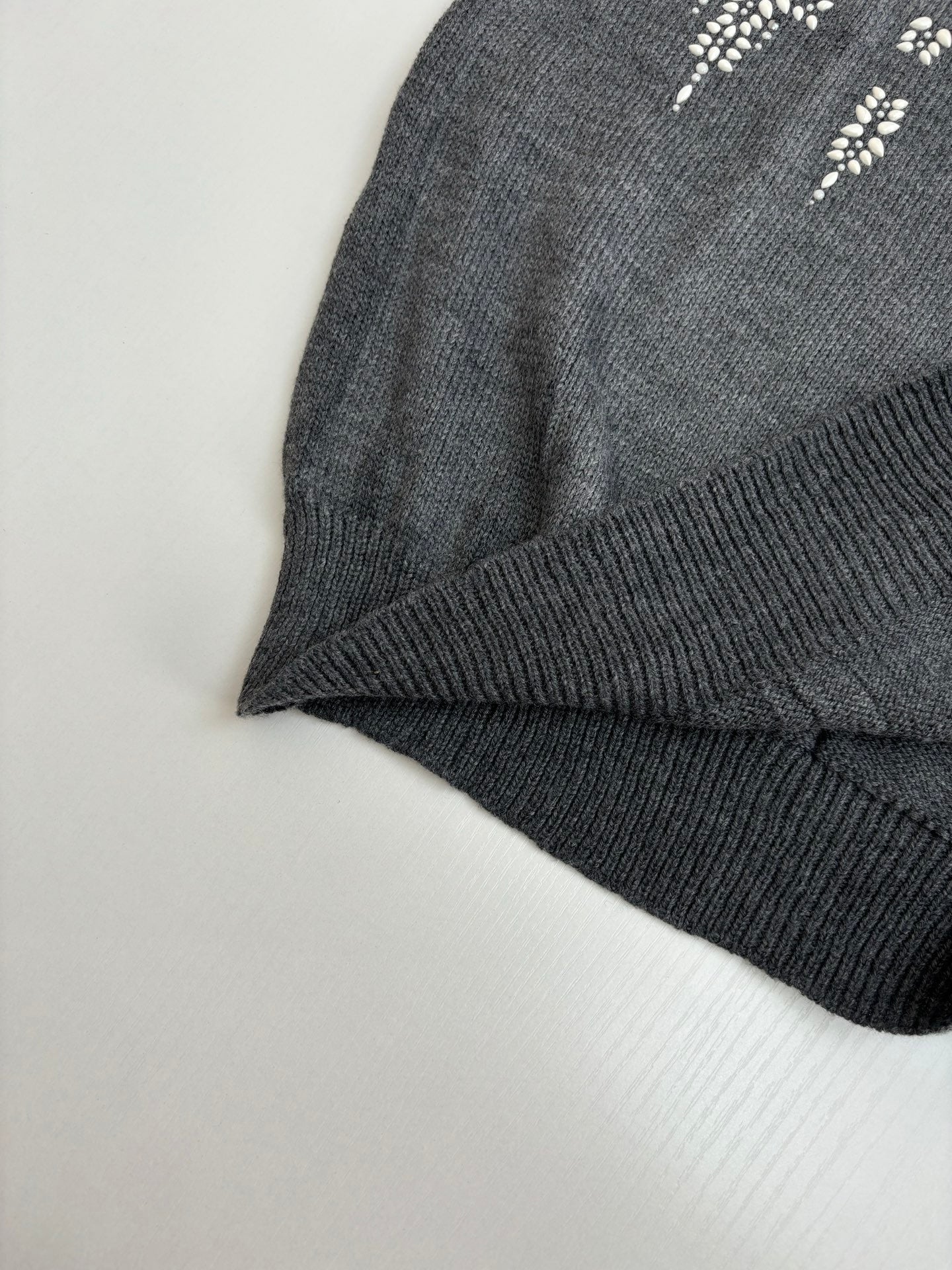 Dark gray sweater sleeve cuff and ribbed hem with white motif detailing