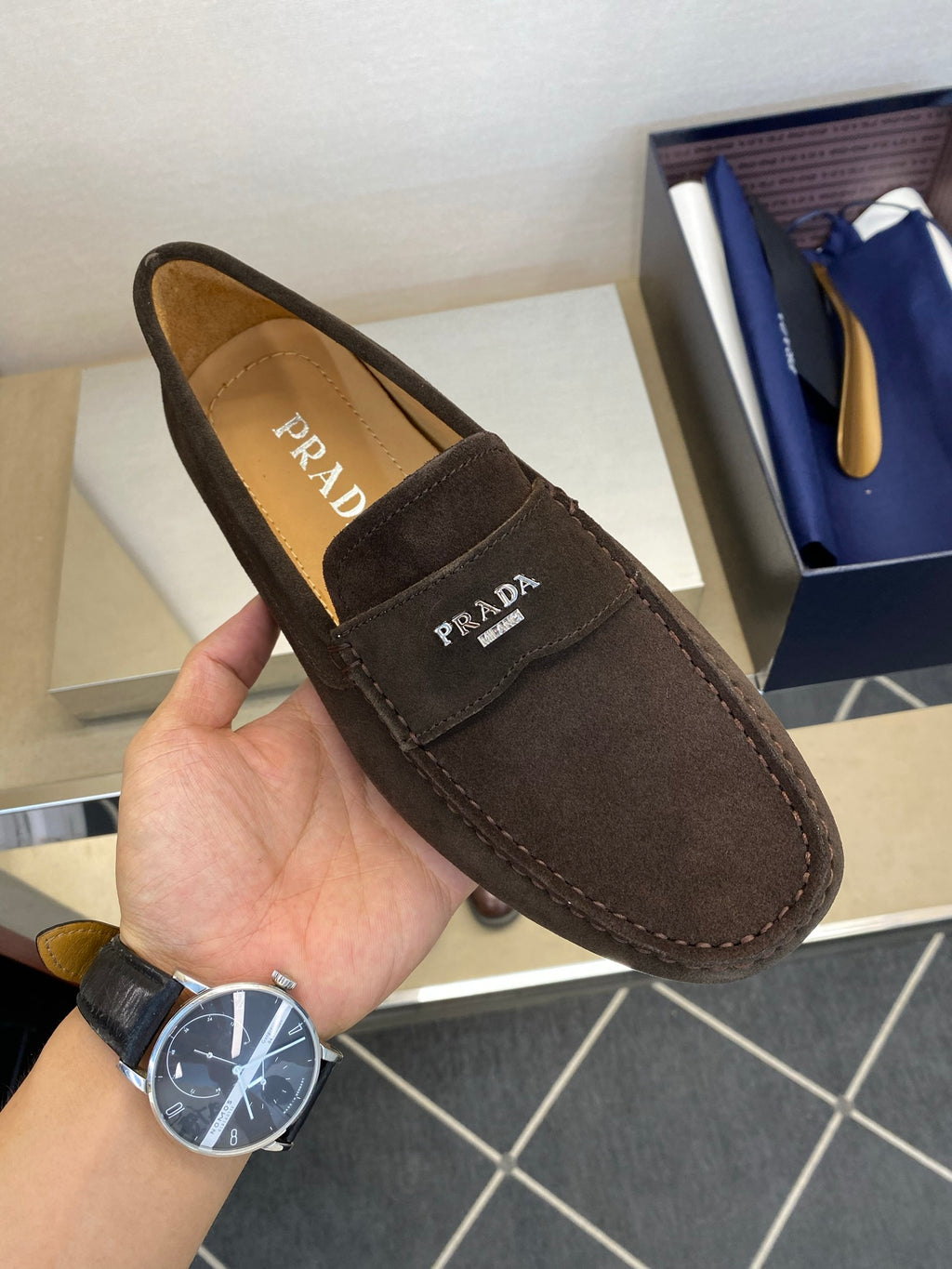 Brown suede loafer with Prada logo patch and side strap detail, stitched edges