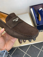 Close-up of brown suede loafer with Prada logo patch and contrast stitching