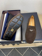 Brown suede loafer with Prada logo, one showing patterned outsole design