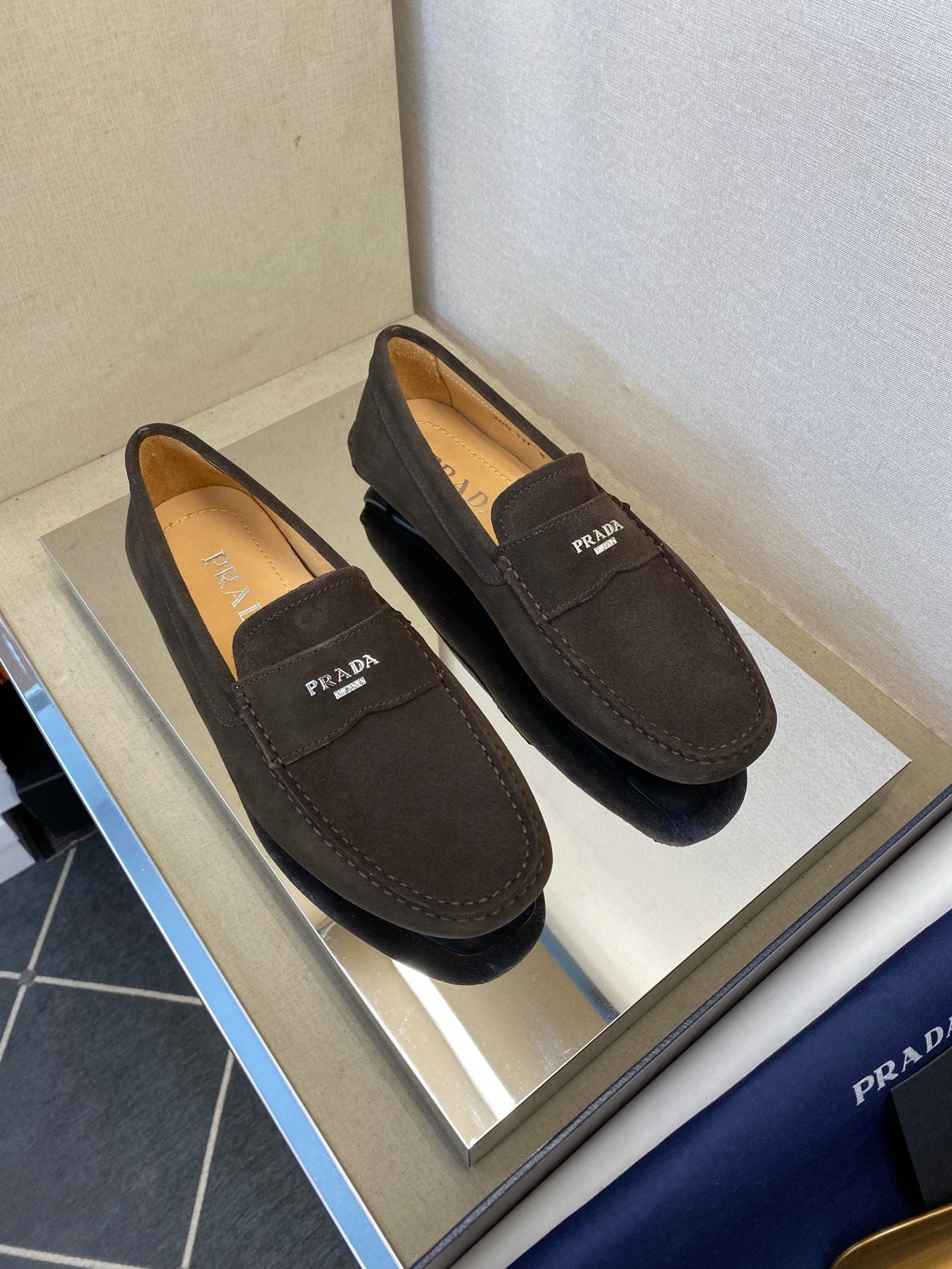 Pair of brown suede loafers with Prada logo tabs and stitched trim