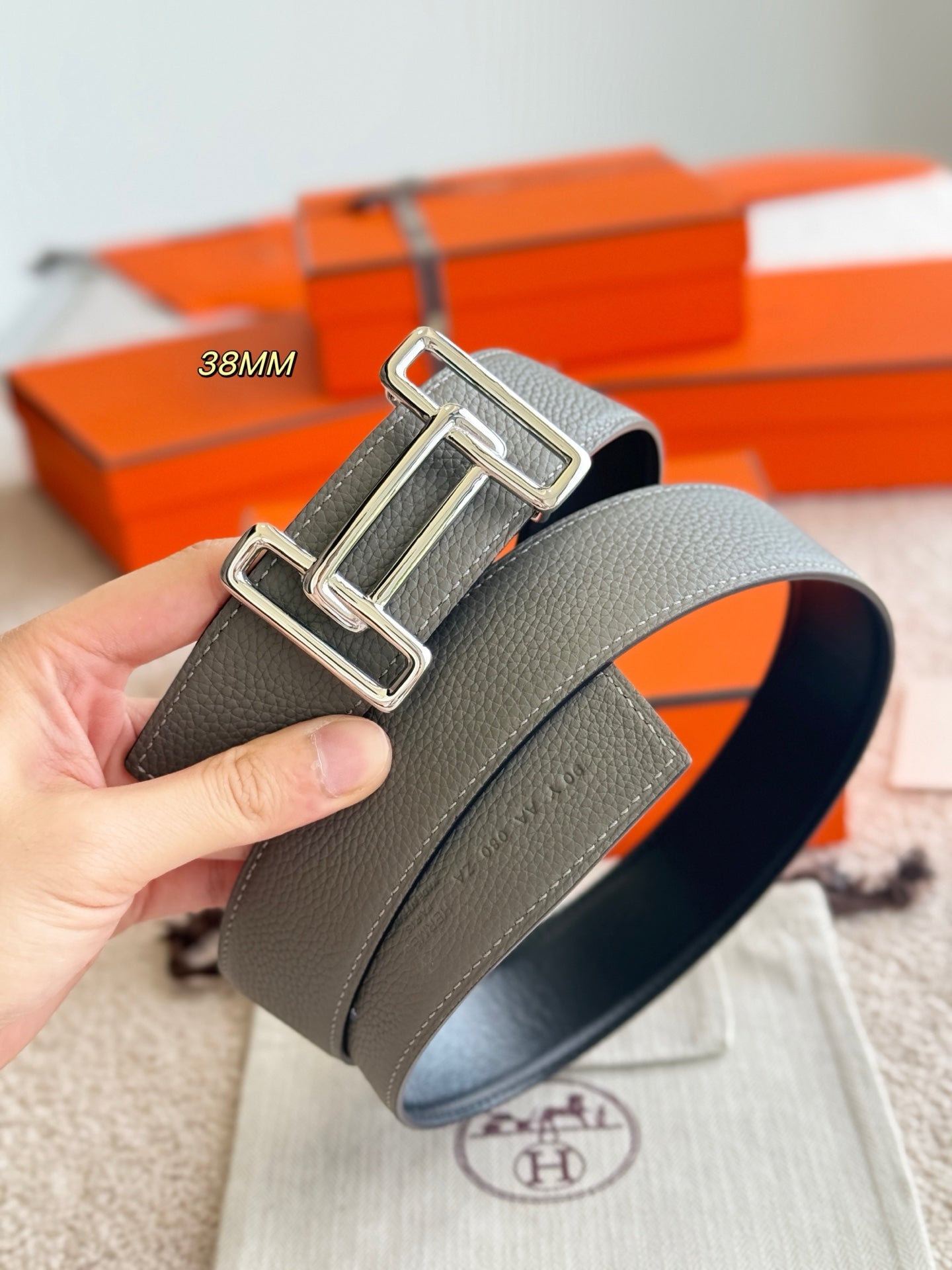Hermes reversible leather belt, close-up of silver buckle on light gray strap