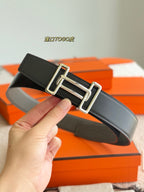 Hermes reversible leather belt, dark strap with silver buckle, held in hand