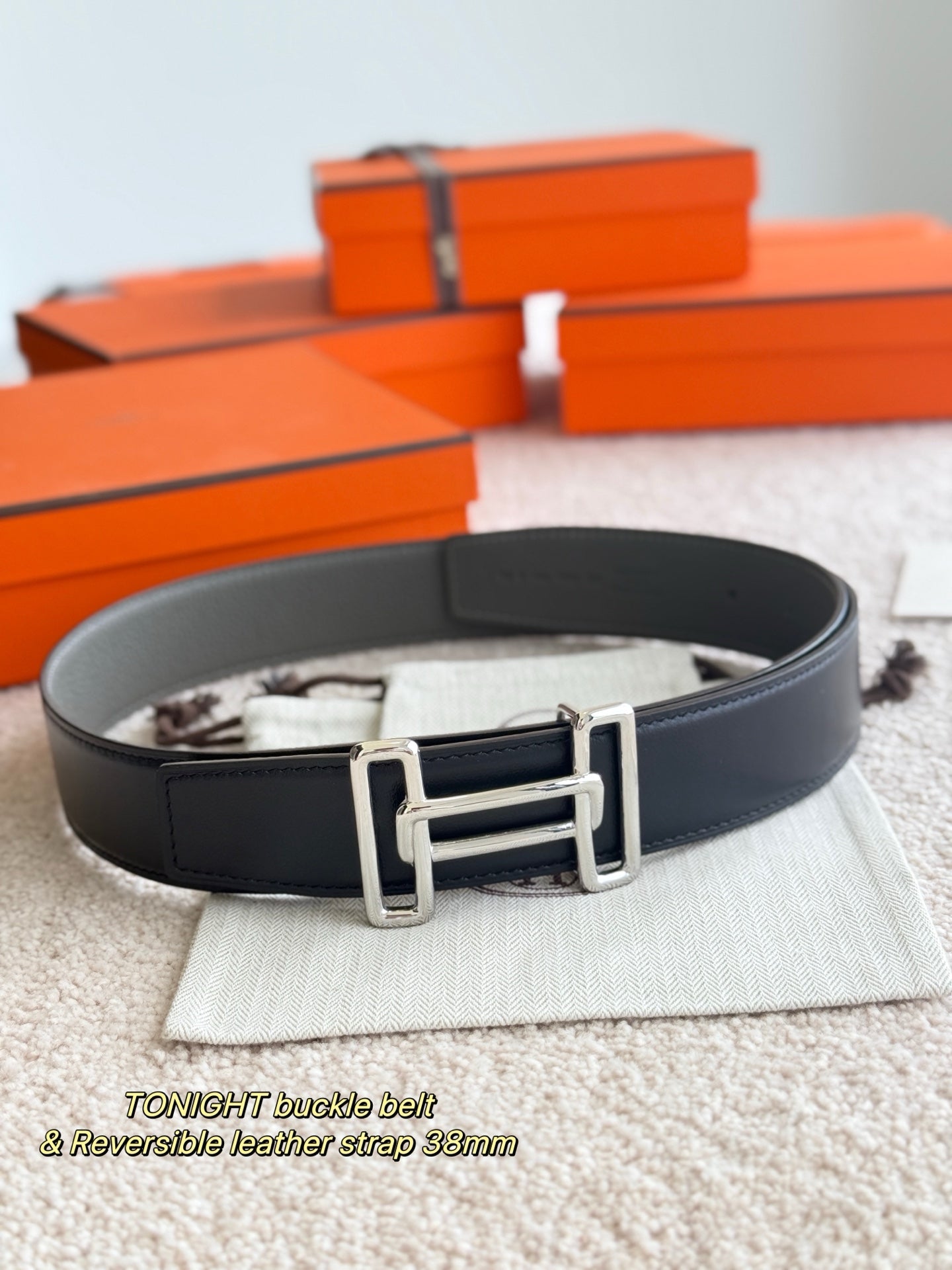 Hermes reversible belt, dark gray leather strap with silver buckle, shown flat on pouch