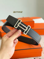 Hermes dark leather belt with silver buckle, hand holding close-up