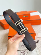 Hermes belt with dark textured leather and silver buckle, close-up
