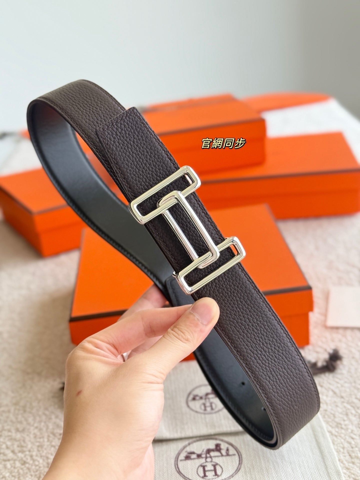 Hermes belt with dark textured leather and silver buckle, close-up