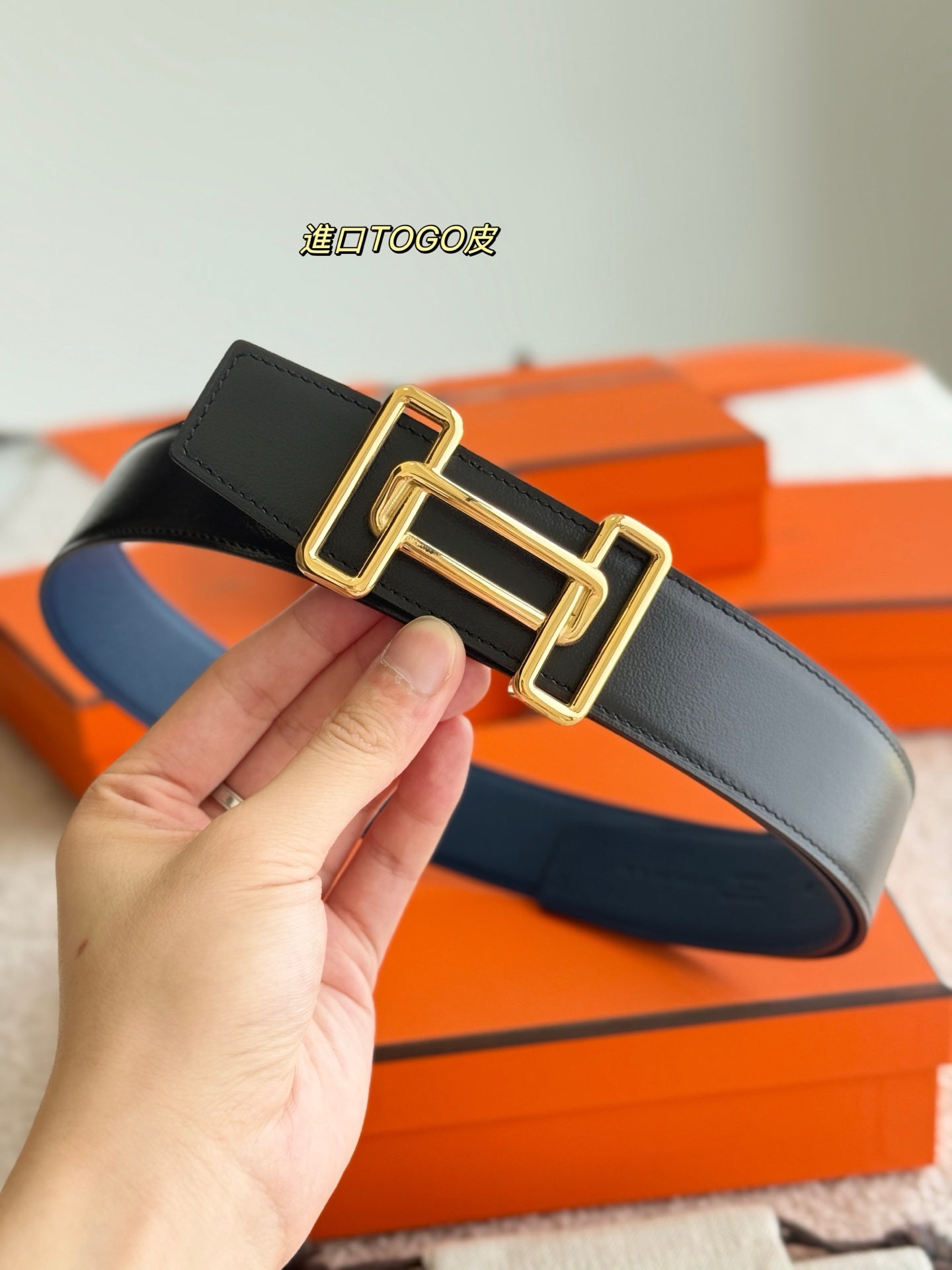 Reversible leather belt showing dark and blue sides with gold-tone buckle
