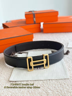 Black leather belt with gold buckle and double bar design, laid on fabric pouch.