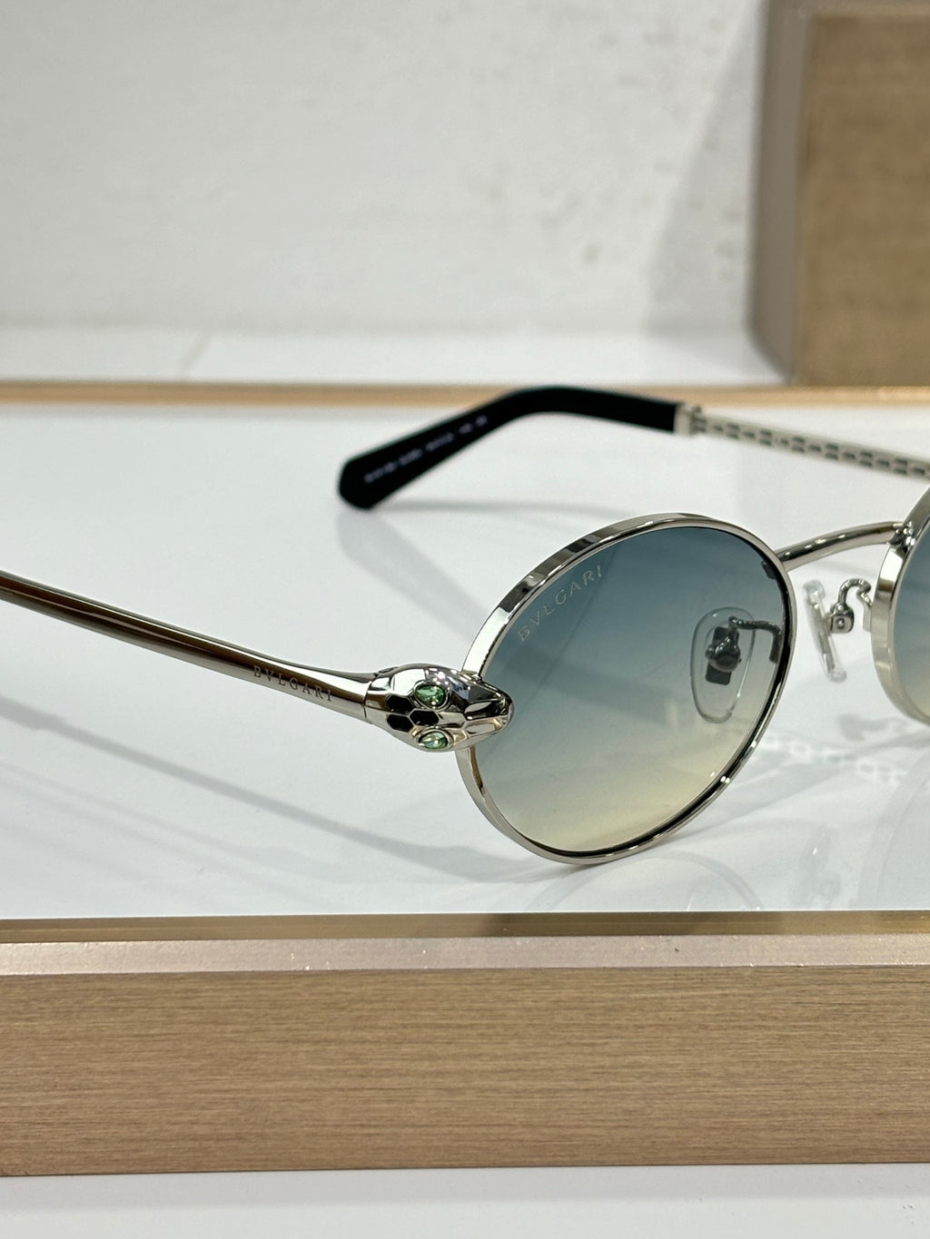 Round sunglasses with silver metal frame, blue-tinted lenses, and black temple