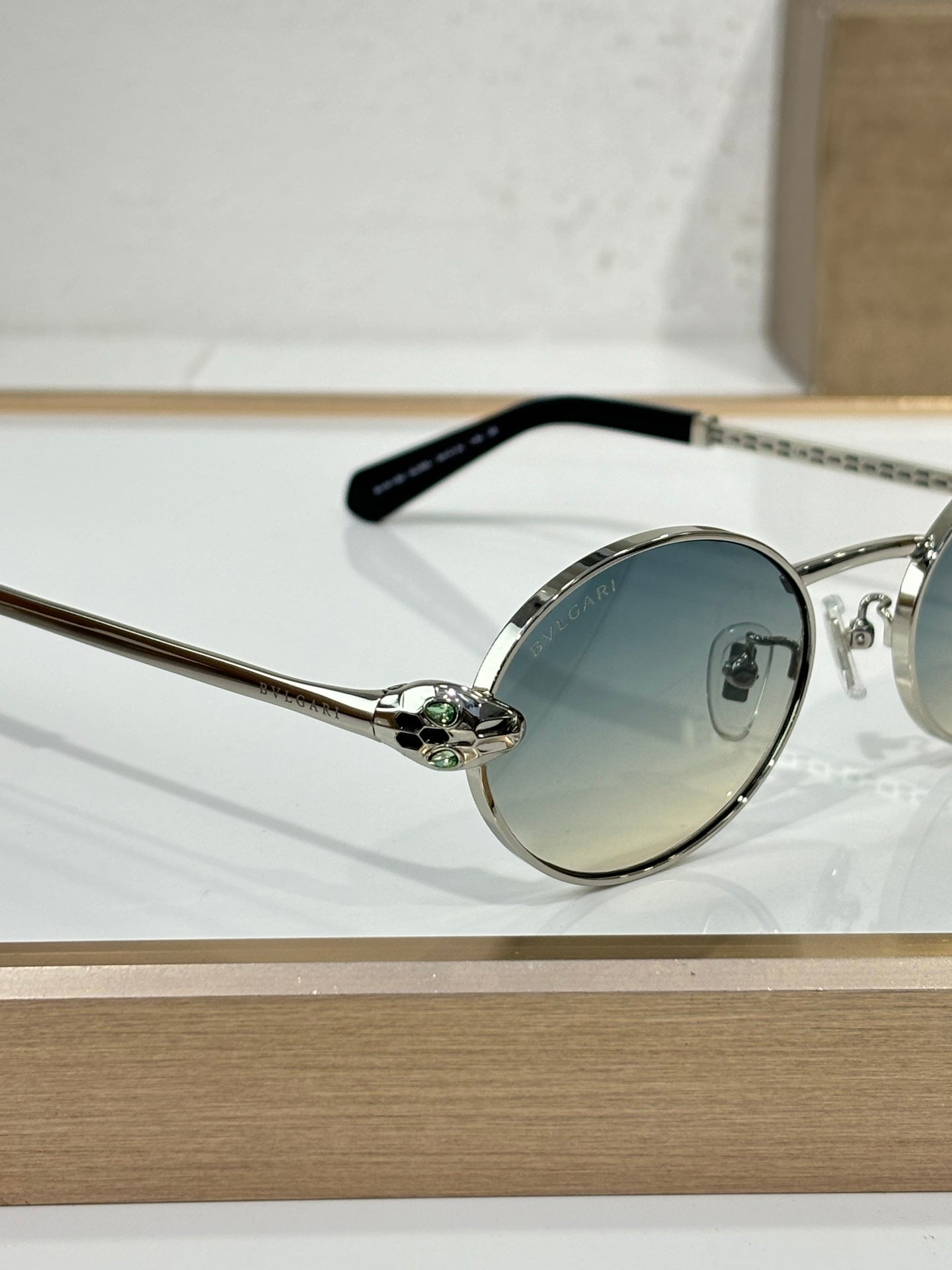 Round sunglasses with silver metal frame, blue-tinted lenses, and black temple