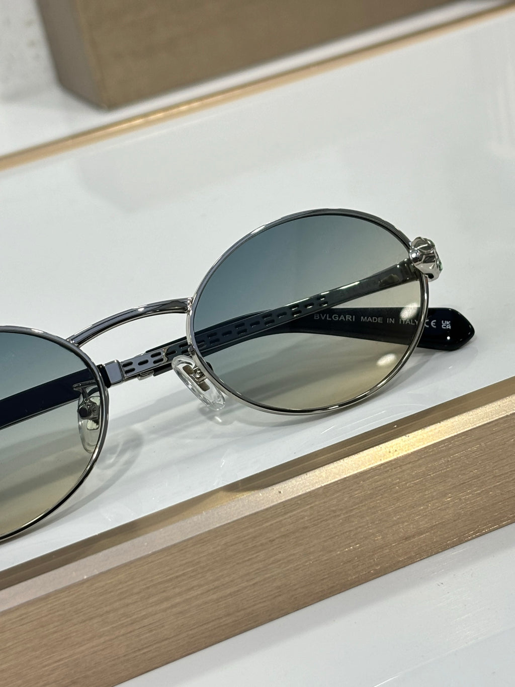Round sunglasses with silver metal frame, blue lenses, and engraved temple detail